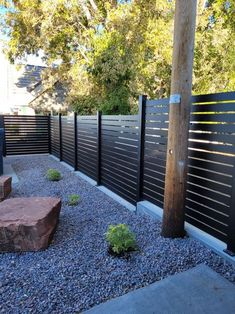 a fenced in area with rocks and plants