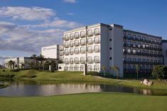 a large white building sitting on top of a lush green field next to a lake