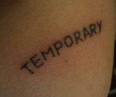 the word temporary is written in cursive font on someone's leg,