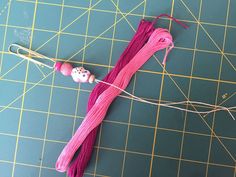 a piece of pink thread and beads on a cutting board