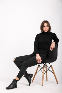 a woman sitting on top of a wooden chair wearing black pants and high heeled shoes