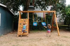 two children playing on a wooden swing set