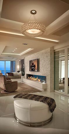 a modern living room with white furniture and large windows overlooking the ocean at night time