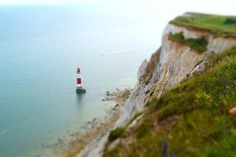 a red and white lighthouse sitting on the side of a cliff next to the ocean