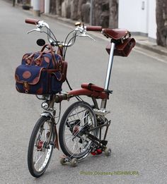 a bicycle parked on the street with a bag strapped to it's handlebars