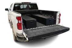 the back end of a white pickup truck with two black boxes in it's bed