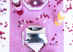 a pink table with confetti and other items on it, including an empty bottle