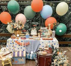 a table topped with lots of cake and balloons