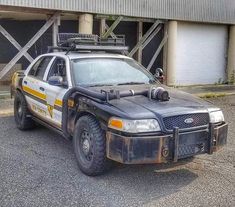 an old police car parked in front of a building with two garage doors on the side