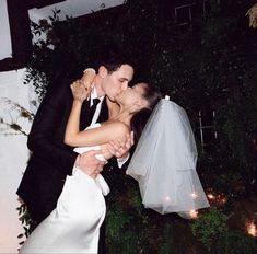 a bride and groom kissing outside at night