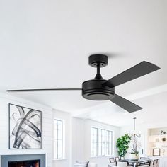 a black ceiling fan in a white living room with a fireplace and dining table next to it