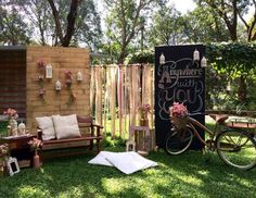 an outdoor seating area is decorated with flowers and wooden signs, including a bicycle parked next to the bench