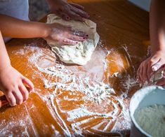 three people are kneading dough on a table