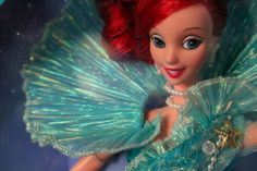 a close up of a doll with red hair and blue eyes wearing a green dress