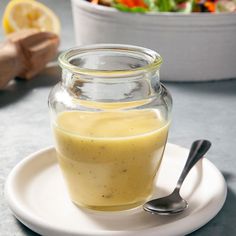 a glass jar filled with liquid sitting on top of a white plate next to a salad