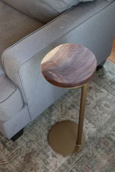 a small wooden table sitting on top of a metal stand in front of a couch