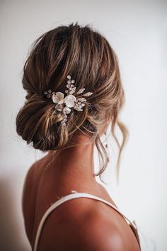 a woman wearing a wedding hair comb with flowers in her hair, looking back at the camera