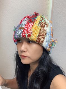 a woman with long black hair wearing a multicolored crochet knit hat