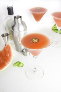 three martini glasses filled with pink liquid and garnished with a slice of watermelon