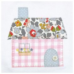 a pink and white house with flowers on the roof is embroidered onto it's side