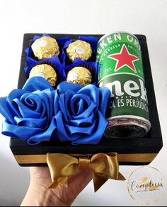 a hand holding a box of chocolates and a can of beer with blue roses