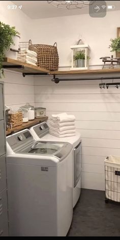 a washer and dryer in a room with shelving on the wall behind them