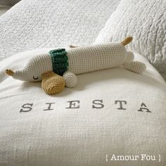 a stuffed animal laying on top of a bed next to a pillow that says siestta