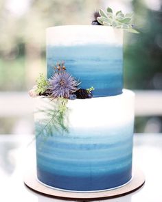 two tiered blue and white cake with flowers on top