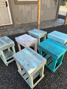 four wooden tables and two stools sitting on gravel