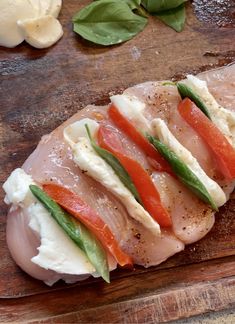 sliced meat with vegetables and cheese on a wooden cutting board