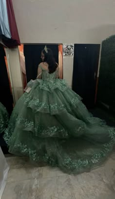 a woman in a green ball gown sitting on the floor looking at her reflection in a mirror