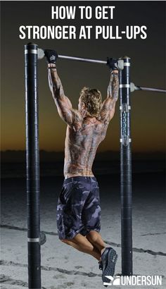 a man doing pull ups on the beach with his arms and legs bent over poles