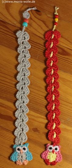 two crocheted items are hanging on a wooden table and one is red, the other gray