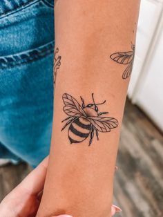 a woman's arm with a tattoo of a bee and two bees on it