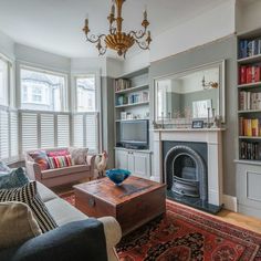 a living room filled with furniture and a fire place under a chandelier next to a window