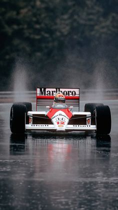 a man driving a race car on top of a body of water with steam pouring out of it