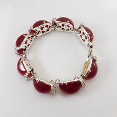 Kramer red moonglow bracelet is a beautiful example of mid-century costume jewelry.  Unique dome shaped deep red moonstones are set in silver tone metal.  Curved spacers are on the end of each link and are set with baguette rhinestones and tiny chatons.  The lovely Kramer bracelet is about 1/2 inch wide and about 6 3/4 inch long, closing with a fold over clasp.  Top to bottom the bracelet sits about 3/8 inches off the base.  There are two tiny chatons missing and some slight yellowing a few ston Retro Red Bracelet Jewelry, Vintage Rhinestone Jewelry, Daisy Jewelry, Purple Daisy, Rhinestone Ring, Moon Glow, Message Jewelry, Bracelet Vintage, Jewelry Unique