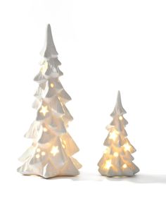 two small white christmas trees with lights on them