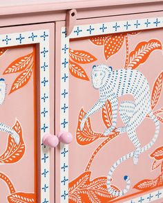 an orange and white painted cabinet with pink knobs on the handles, decorated with monkeys