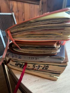 a stack of books sitting on top of a wooden table next to a red ribbon