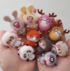 a hand is full of small needle - felt animal figurines in various colors and sizes