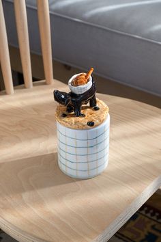 a small dog figurine sitting on top of a table next to a bowl of food