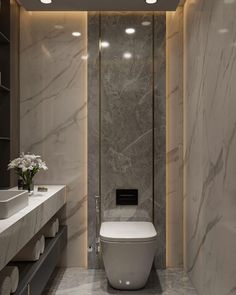 a modern bathroom with marble walls and flooring, along with a white toilet in the center