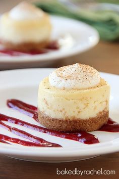 two small desserts on white plates with red sauce and whipped cream drizzled over them