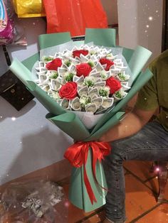 a man sitting on a chair holding a bouquet of flowers