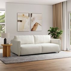 a white couch sitting in a living room on top of a hard wood floor next to a window