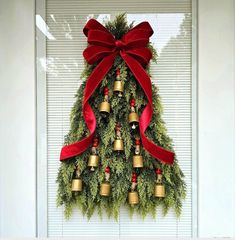 a christmas tree with bells hanging from it's side and a red bow on top