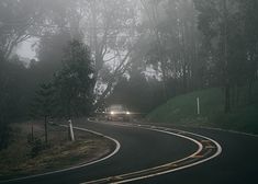 the car is driving down the road in the fog