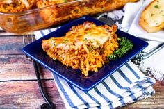 a blue plate topped with lasagna covered in cheese and parmesan bread