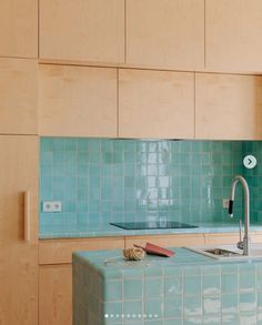 a kitchen with blue tiles on the wall and wooden cabinets in the backround